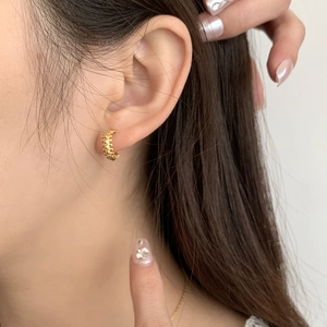 Close-up of golden 925 sterling silver hoop earrings with textured spine pattern