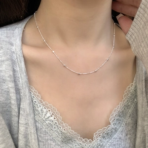 Close-up of minimalist S925 sterling silver beaded choker necklace worn on collarbone