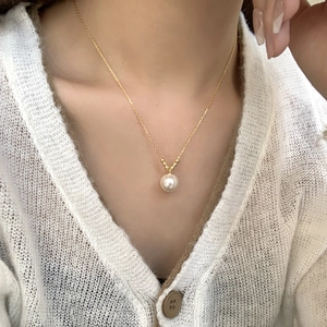 Close-up of minimalist S925 silver necklace with white pearl pendant on elegant gold chain