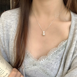 Detail of an S925 silver necklace with a single round pearl worn by a model