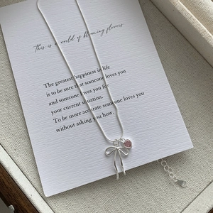 Détail du pendentif nœud et cœur rose en argent S925 sur une carte cadeau artistique