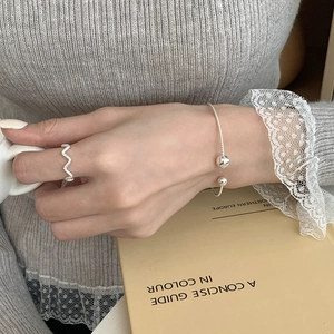 S925 sterling silver beaded twist bangle and wave ring on a model with knitwear