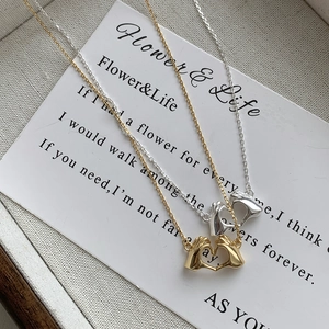 Detail of gold and silver S925 sterling silver necklaces with heart gesture pendants