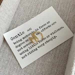 Détail macro d'un earcuff géométrique doré avec une finition en métal brossé mat