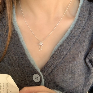 Collier avec pendentif cœur rose et nœud argenté porté par un mannequin