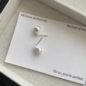 Macro detail of S925 sterling silver bean stud earrings with matte brushed texture