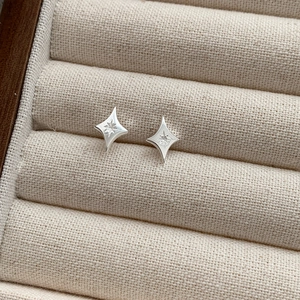 Macro shot of silver four-pointed star stud earrings with an eight-pointed star pattern