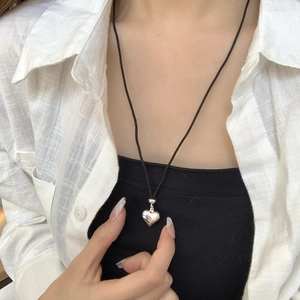 Détail d'un pendentif cœur en argent 925 minimaliste avec cordon noir ajustable
