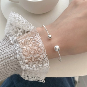 Close-up of S925 sterling silver twist bangle with sphere ends on a model's wrist