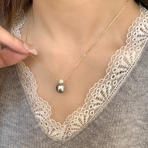 Close-up of S925 silver necklace featuring a dark grey round pearl pendant on a model