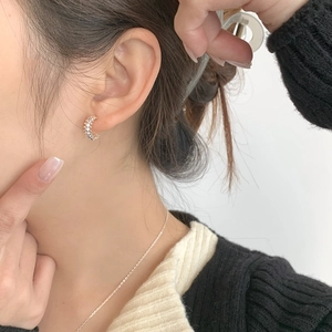 Detail of 925 sterling silver hoop earrings with a textured geometric surface on model