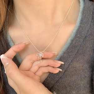 Collier en argent S925 avec pendentif cœur rose et nœud papillon porté par un mannequin