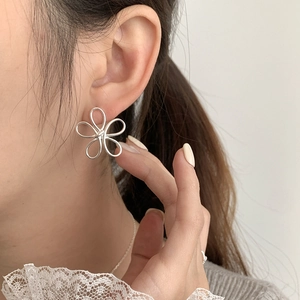 Minimalist S925 sterling silver hollow flower stud earrings worn by a female model