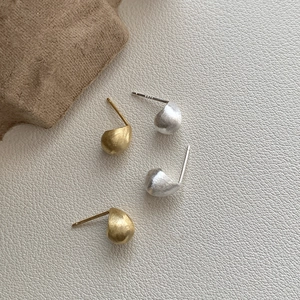 Macro view of S925 sterling silver bean stud earrings with matte brushed metal texture
