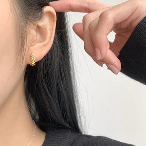 Minimalist 925 sterling silver huggie earrings with gold textured rivet design on ear