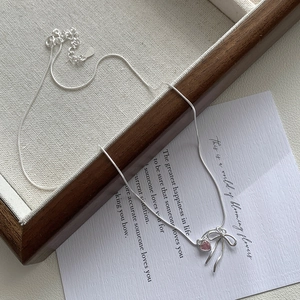 Collier en argent S925 avec pendentif cœur rose et nœud sur fond esthétique chic