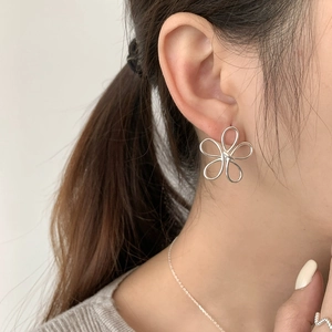 Minimalist S925 sterling silver hollow flower stud earrings worn by a model