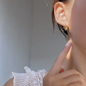 Close-up of elegant gold drop earrings in an irregular geometric design on model