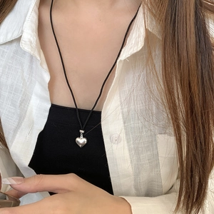 Détail macro du pendentif cœur en argent S925 poli sur un cordon noir réglable de collier