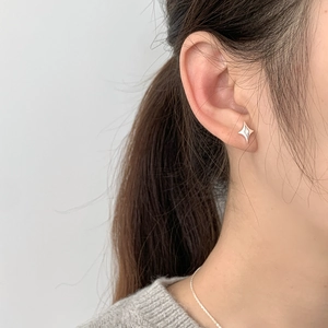 Detail of S925 sterling silver star stud earring with zircon on a model's ear
