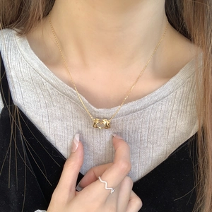 Detailed view of a gold S925 silver necklace with a heart gesture pendant on a model