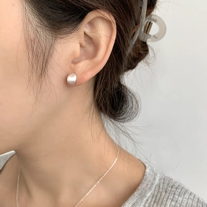 Detail of matte S925 sterling silver bean earrings with a brushed metallic texture