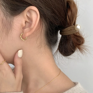 Detailansicht der C-förmigen Creolen mit Blattstruktur und Goldschmuck am Model getragen