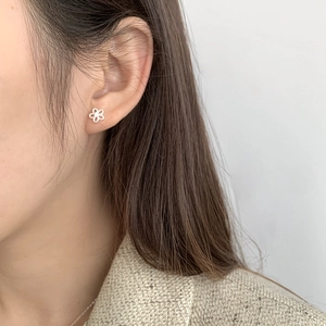 Detailed view of tiny minimalist hollowed S925 silver flower stud earring on ear