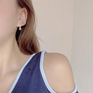 Close-up of a model wearing minimalist geometric silver earrings with a high-polished finish