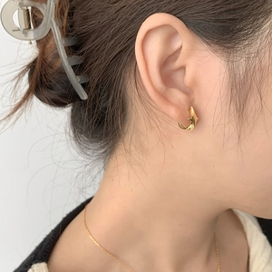 Close-up of gold 925 sterling silver star-shaped hoop earrings worn on a model ear