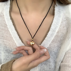 Collier minimaliste avec pendentif cœur doré sur cordon noir réglable porté par un mannequin