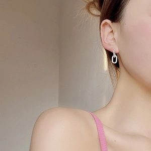 Detail of interlocking silver knot earrings worn on ear showing drape and size
