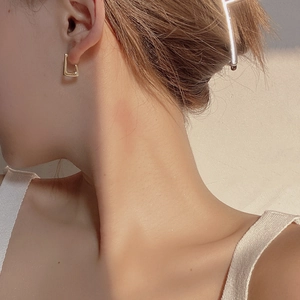 Minimalist geometric gold 925 silver earring worn by a model in soft natural lighting