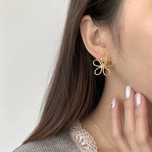 Close-up of elegant gold hollow flower stud earring worn by model on ear