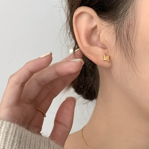 Close-up of a minimalist gold star stud earring worn on a model for an elegant look