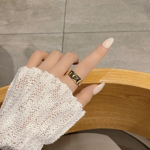 Detail of a wide gold ring featuring a quilted diamond pattern on a finger