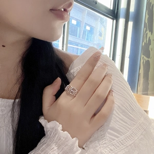 Detailed view of silver wide-band ring with hollow BB letter design on finger