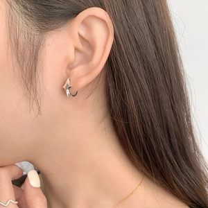 Minimalist 925 sterling silver star-shaped hoop earrings worn by a female model