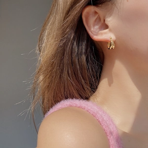 Boucles d'oreilles doubles dorées minimalistes avec design géométrique torsadé poli sur modèle