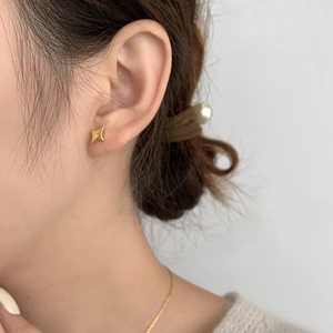 Close-up of minimalist gold star stud earring worn by a model for a refined look
