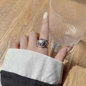 Detail view of a S925 sterling silver hammered ring worn on a finger in a cozy setting