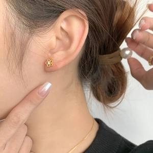 Close-up of minimalist gold hollow flower earring with zircon inlay worn by a model