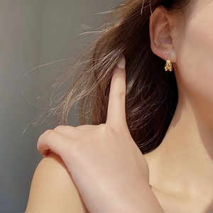 Gros plan d'élégantes créoles dorées doubles en argent S925 sur l'oreille du mannequin