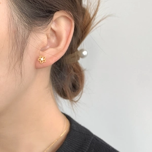 Detailed view of tiny 925 sterling silver gold flower stud earrings with center zircon