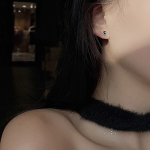 Close-up of a minimalist S925 sterling silver smiley face stud earring on ear