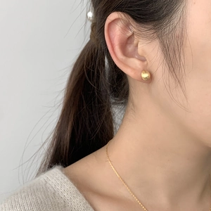 Close-up of minimalist gold drop earrings and necklace with a matte brushed finish on model
