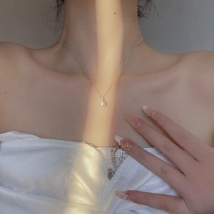 Elegant natural pearl pendant on silver necklace worn by model in soft natural sunlight