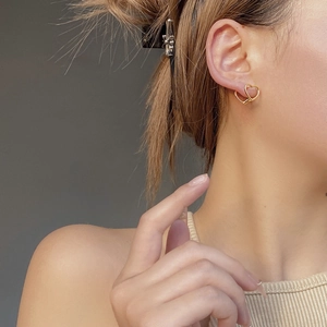 Close-up of a hollow heart-shaped gold earring worn on the ear for a delicate look