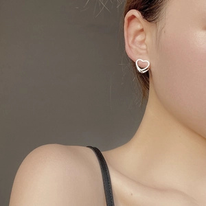 Minimalist S925 sterling silver hollow heart earrings worn by a model in a close-up view