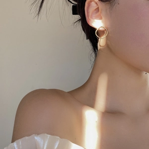 Gros plan sur des boucles d'oreilles géométriques irrégulières dorées portées par un mannequin